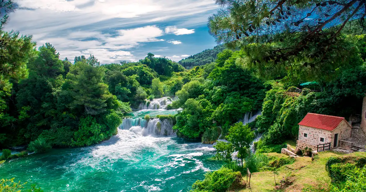 White park boat crossing the green Krka river canyon towards Skradin on the short-day Krka waterfalls tour from Split